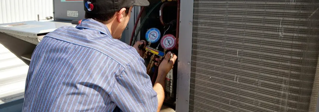 HVAC technician servicing a condenser unit in North Platte